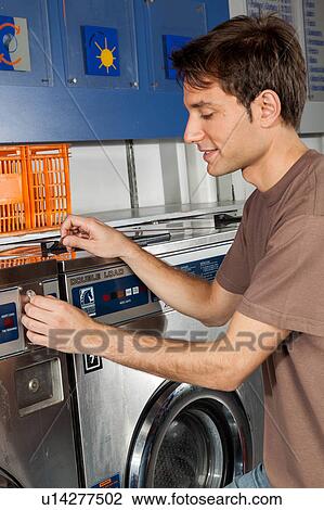 Stock Image - Man washing clothes in the laundry. Fotosearch