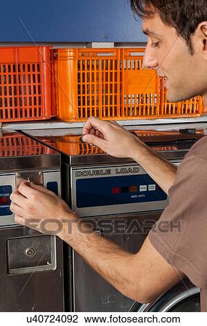 Stock Image - Man washing clothes in the laundry. Fotosearch