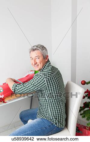 Stock Image - Man wrapping gifts and smiling. Fotosearch