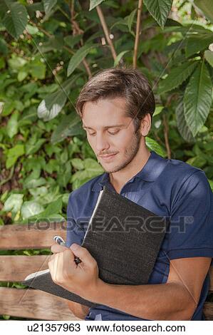 Stock Image - Man writing in the park. Fotosearch