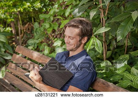 Stock Image - Man writing in the park. Fotosearch
