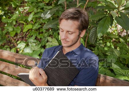 Stock Photo - Man writing in the park. Fotosearch