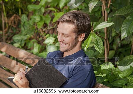 Stock Photography - Man writing in the park. Fotosearch