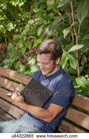 Stock Photography - Man writing in the park. Fotosearch