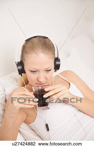 Stock Image - Pretty woman listening to music and drinking coffe. Fotosearch