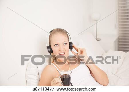 Stock Photo - Pretty woman listening to music and drinking coffe. Fotosearch