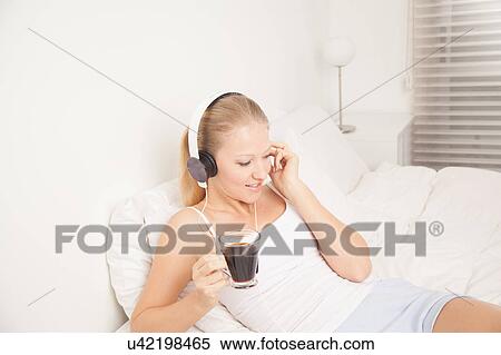 Stock Photography - Pretty woman listening to music and drinking coffe. Fotosearch