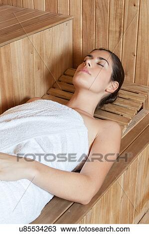 Stock Image - Pretty woman lying inside the sauna. Fotosearch