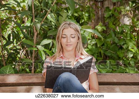 Stock Photo - Pretty woman reading a book in the park. Fotosearch