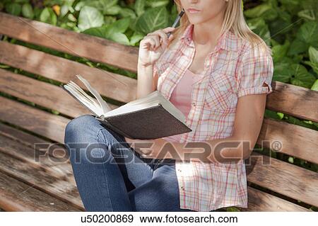 Stock Photo - Pretty woman reading a book in the park. Fotosearch