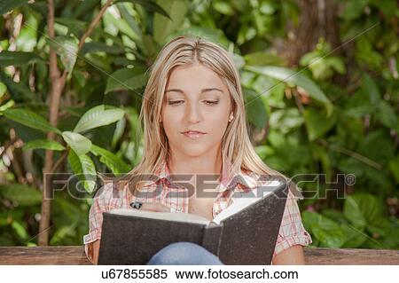 Stock Photography - Pretty woman reading a book in the park. Fotosearch