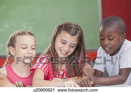 Stock Image - Pupils reading a book. Fotosearch