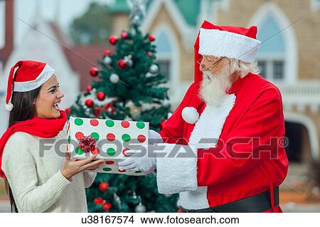 Picture - santa giving a gift to a young woman. Fotosearch