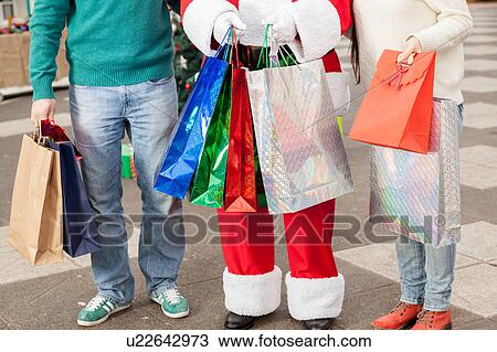 Stock Image - Santa holding a lot of bags. Fotosearch