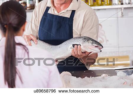 Stock Photograph - Seller of seafood holding a fish. Fotosearch