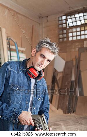 Serious carpenter holding a drill View Large Photo Image Stock Photograph - Serious carpenter holding a drill. Fotosearch