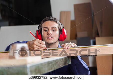 Serious carpenter measuring a piece of wood View Large Photo Image Stock Image - Serious carpenter measuring a piece of wood. Fotosearch
