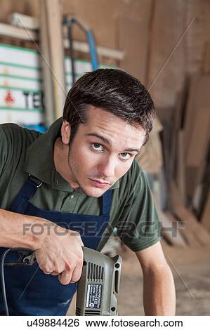 Stock Photograph - Serious man working with a drill. Fotosearch