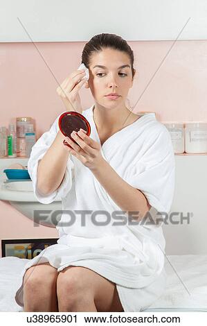 Stock Image - Serious woman cleans your face with a cotton. Fotosearch