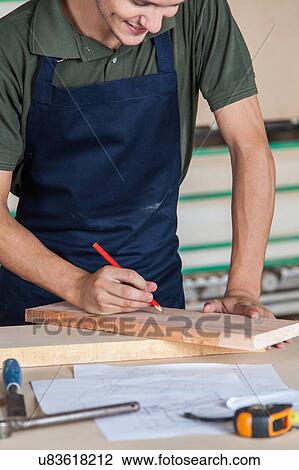 Stock Image - Smiling carpenter in his desk. Fotosearch