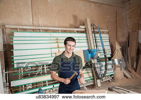 Stock Photo - Smiling carpenter working with a chisel. Fotosearch