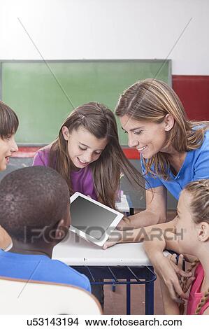 Students and teacher looking at tablet View Large Photo Image Picture - Students and teacher looking at tablet. Fotosearch