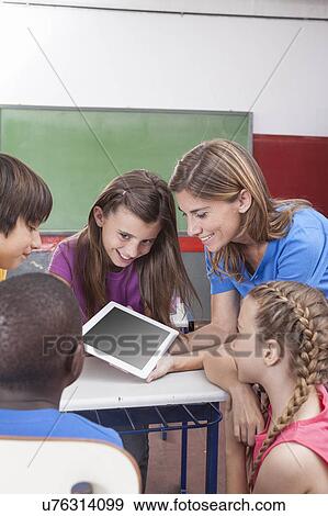 Students and teacher looking at tablet View Large Photo Image Stock Photo - Students and teacher looking at tablet. Fotosearch