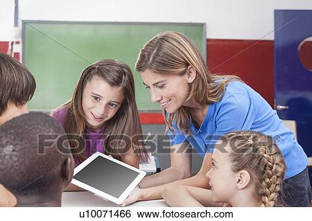 Students and teacher looking at tablet View Large Photo Image Stock Photograph - Students and teacher looking at tablet. Fotosearch