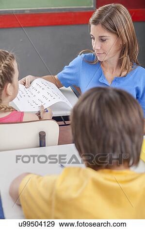 Stock Photo - Teacher giving the exam for girl. Fotosearch