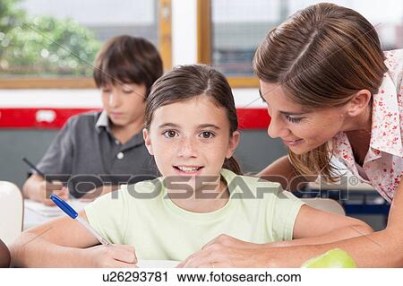 Stock Image - teacher helping a girl in the classroom. Fotosearch