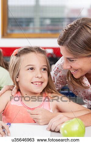 Stock Image - teacher helping a girl in the classroom. Fotosearch