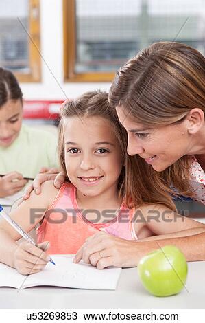 teacher helping a girl in the classroom View Large Photo Image Stock Image - teacher helping a girl in the classroom. Fotosearch