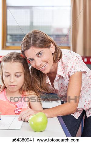 Stock Image - teacher helping a girl in the classroom. Fotosearch