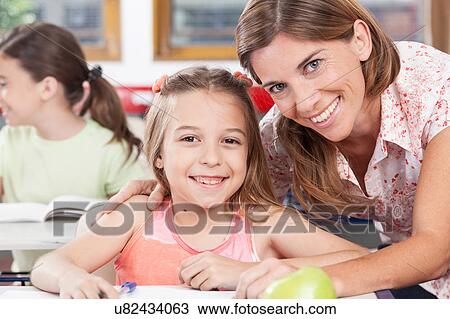 Stock Image - teacher helping a girl in the classroom. Fotosearch