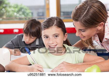 Stock Image - teacher helping a girl in the classroom. Fotosearch