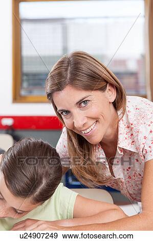 Stock Photo - teacher helping a girl in the classroom. Fotosearch