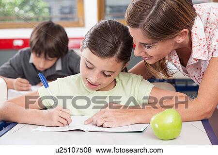 teacher helping a girl in the classroom View Large Photo Image Stock Photo - teacher helping a girl in the classroom. Fotosearch