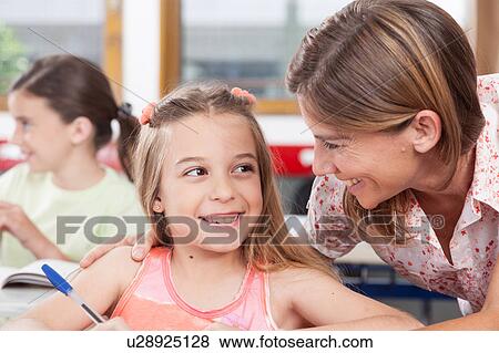 teacher helping a girl in the classroom View Large Photo Image Stock Photo - teacher helping a girl in the classroom. Fotosearch