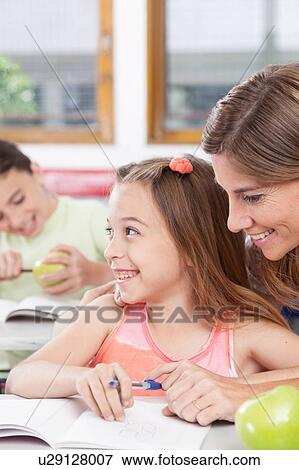Stock Photo - teacher helping a girl in the classroom. Fotosearch