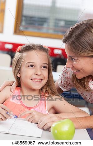 Stock Photo - teacher helping a girl in the classroom. Fotosearch