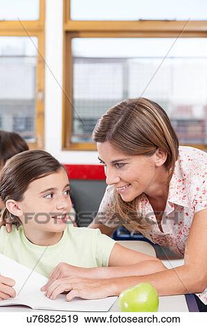 Stock Photo - teacher helping a girl in the classroom. Fotosearch