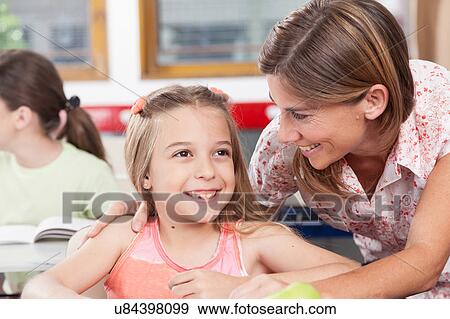 Stock Photo - teacher helping a girl in the classroom. Fotosearch