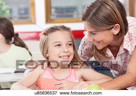 teacher helping a girl in the classroom View Large Photo Image Stock Photo - teacher helping a girl in the classroom. Fotosearch