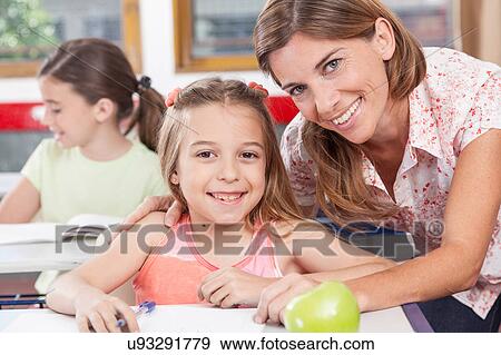 Stock Photo - teacher helping a girl in the classroom. Fotosearch