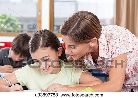 Stock Photo - teacher helping a girl in the classroom. Fotosearch