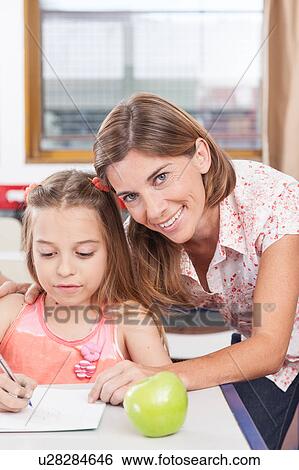 Stock Photograph - teacher helping a girl in the classroom. Fotosearch