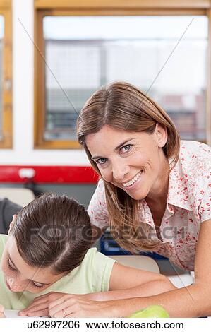 teacher helping a girl in the classroom View Large Photo Image Stock Photograph - teacher helping a girl in the classroom. Fotosearch