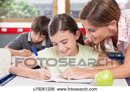 teacher helping a girl in the classroom View Large Photo Image Stock Photograph - teacher helping a girl in the classroom. Fotosearch