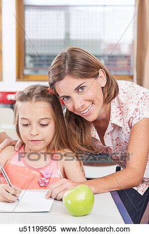 teacher helping a girl in the classroom View Large Photo Image Stock Photography - teacher helping a girl in the classroom. Fotosearch