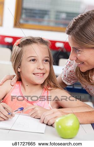 Stock Photography - teacher helping a girl in the classroom. Fotosearch